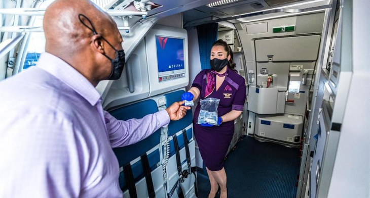 Delta crew member hands out hand sanitising wipes